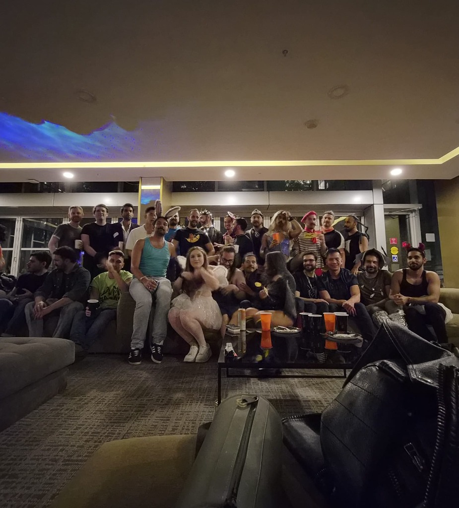 Large group of friends smiling together on and behind the lounge sofa